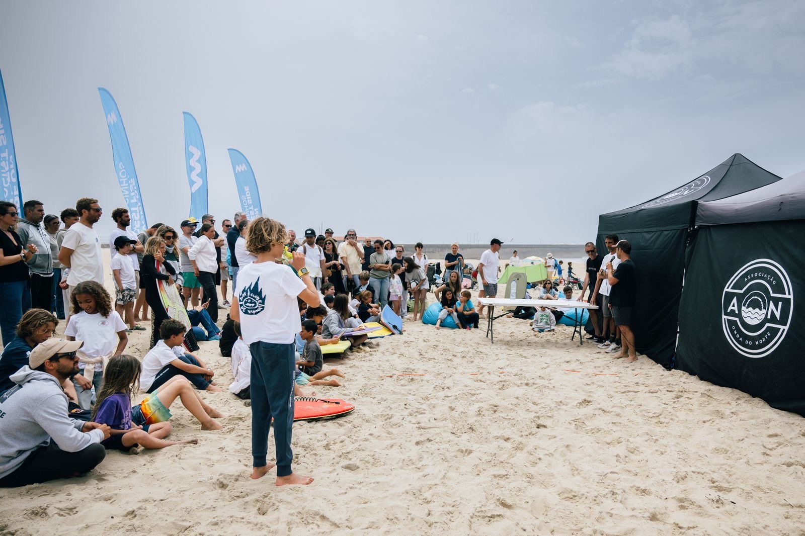 Atletas e famílias reunidos junto à tenda da Associação Onda do Norte